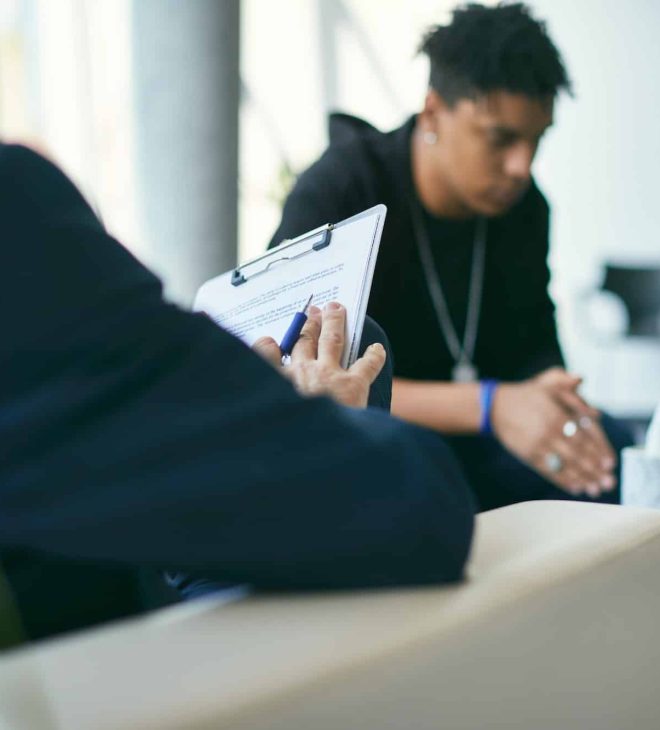 Close-up of psychotherapist doing mental health assessment of teenage boy during therapy session.